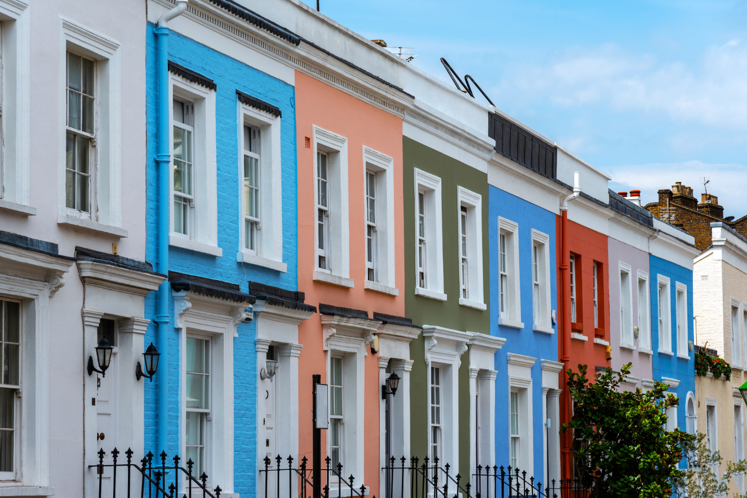 Row of pastel-painted terraced houses with white stucco surrounds and iron railings