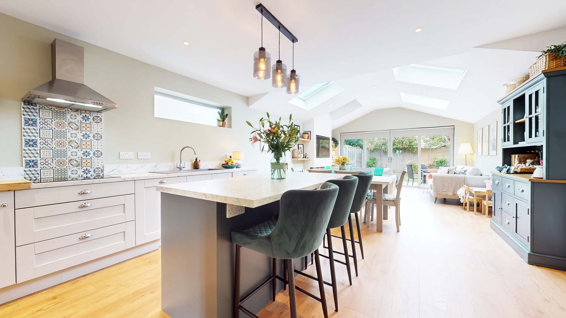 Open-plan kitchen and dining room with an island, bar stools and roof lights